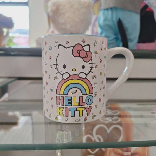 Hello Kitty mug with a rainbow graphic on a glass shelf