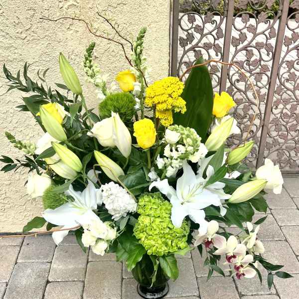 Large floral arrangement with white lilies, yellow roses, and green hydrangea in a vase