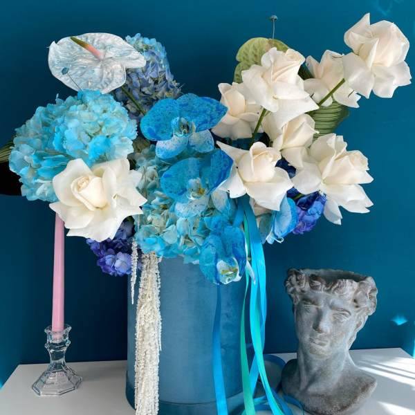 Blue and white floral arrangement in a tall blue box with ribbons