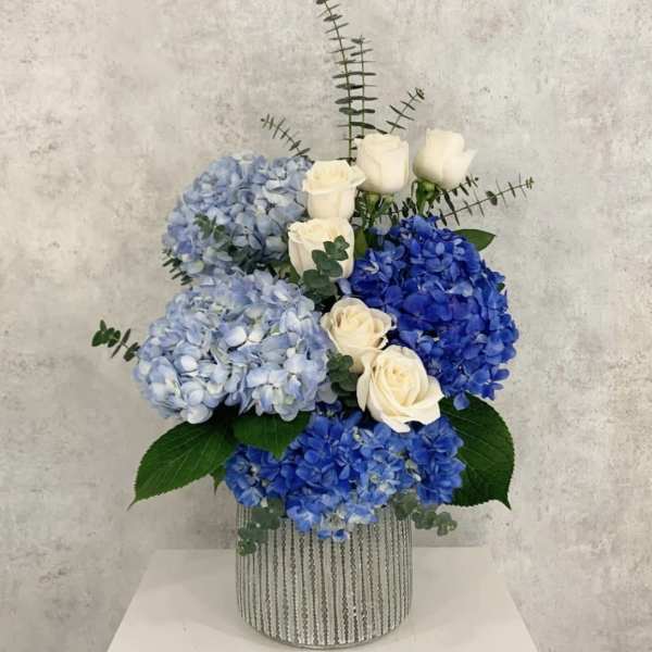 Blue hydrangeas and white roses in a silver striped vase
