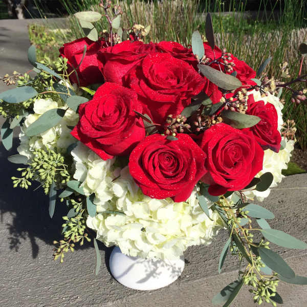 Red roses and white hydrangeas in a white vase