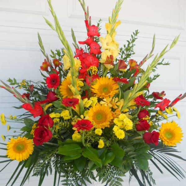 Large arrangement of red and yellow flowers in a white container
