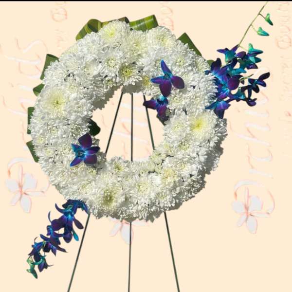 White chrysanthemum wreath with blue-purple orchid accents on a stand
