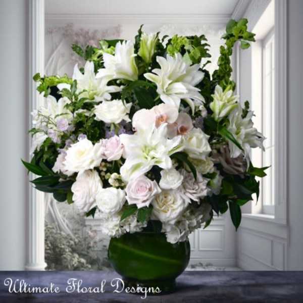 Large white floral arrangement in a green glass vase