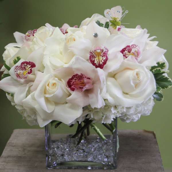 White floral bouquet in a square glass vase with crystal filler
