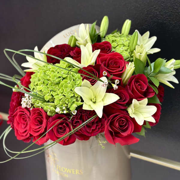 Red roses and white lilies in a beige hatbox
