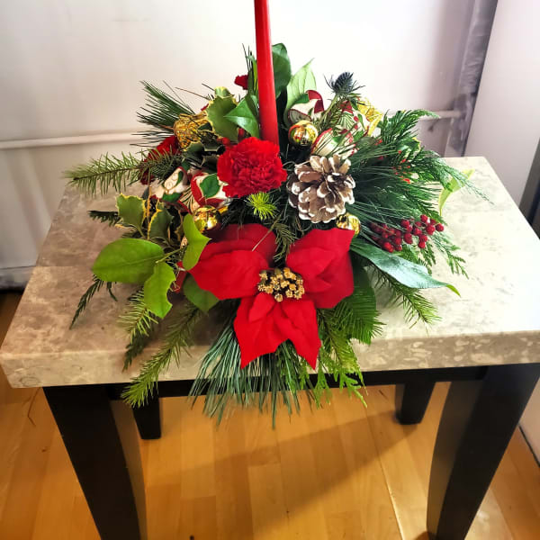 Christmas centerpiece with a red candle, poinsettia, and pinecones