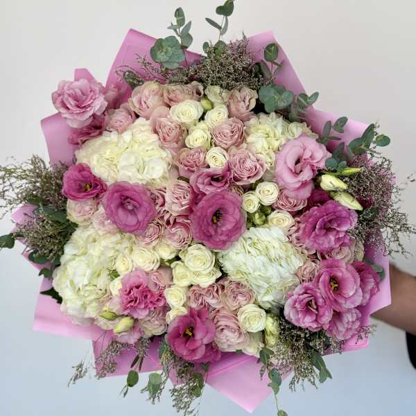 Pink and white bouquet of roses and lisianthus wrapped in pink paper