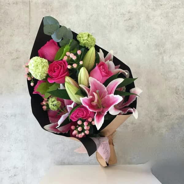 Bouquet of pink lilies and roses wrapped in black paper