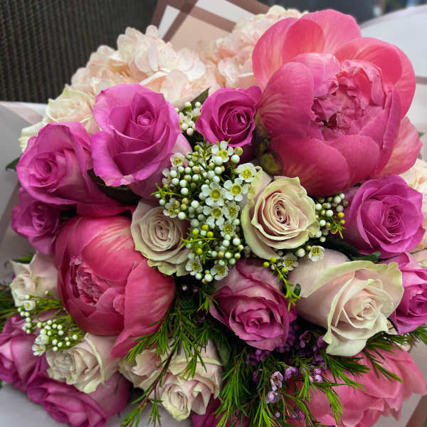 Bouquet of pink peonies and roses with small white filler flowers