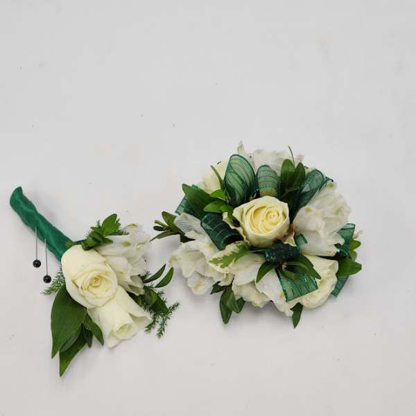 Two white rose boutonnieres with green ribbon accents