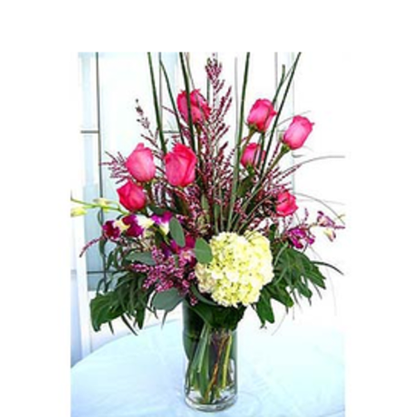 Pink roses and a pale yellow hydrangea in a clear glass vase