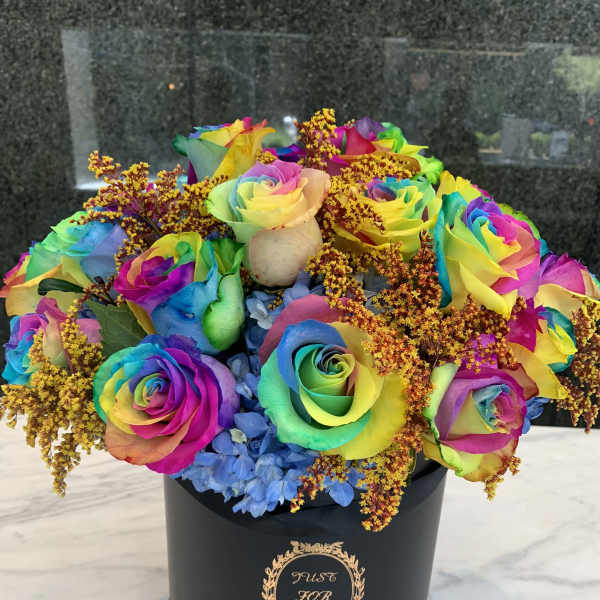 Rainbow roses in a black hatbox with blue hydrangeas