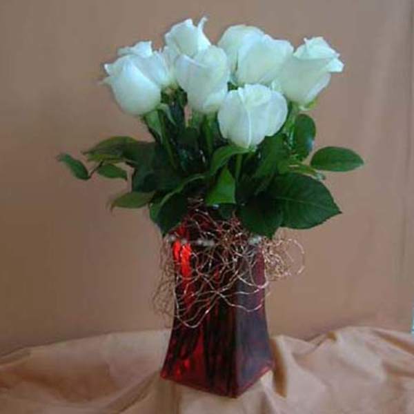 Bouquet of white roses in a red glass vase