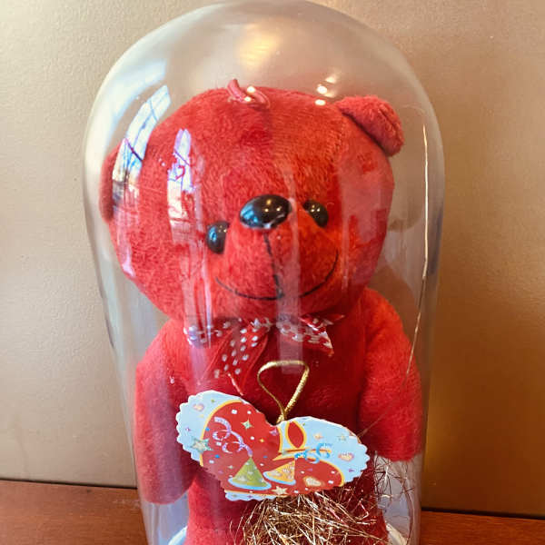 Red teddy bear under a clear dome with a "I Love You" bow