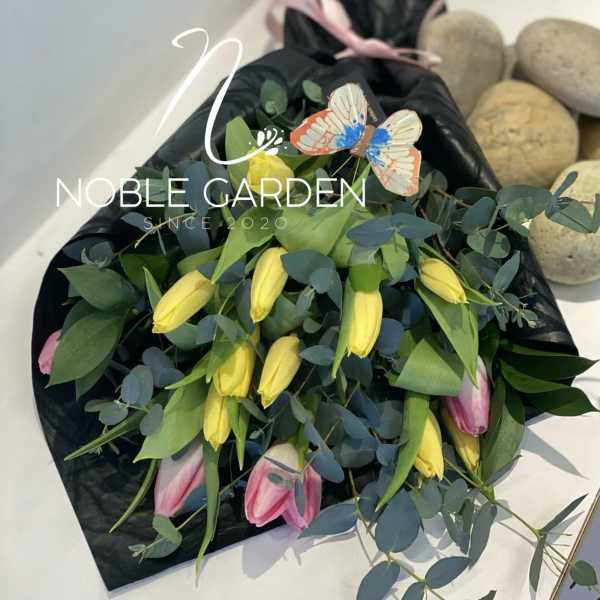 Bouquet of yellow and pink tulips with eucalyptus in black wrap