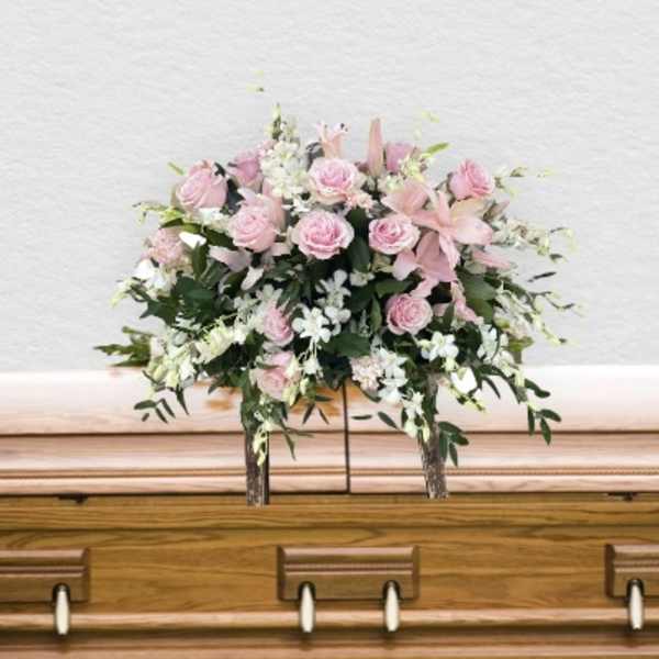 Pink and white floral spray on a wooden casket