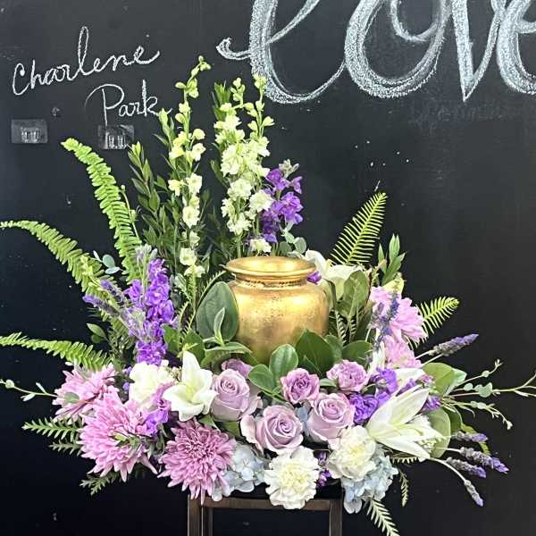 Lavender roses and pink flowers arranged around a gold urn