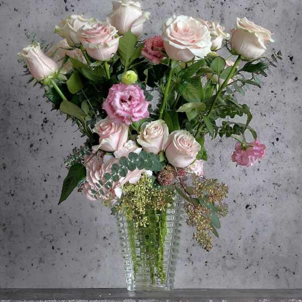Pink and white roses with pink lisianthus in a clear glass vase