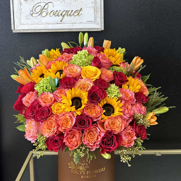 Large bouquet of roses, sunflowers, and lilies in a brown box