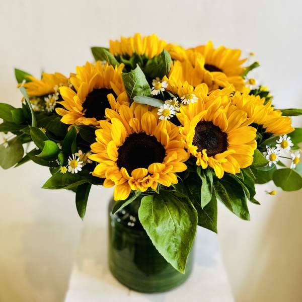 Bouquet of sunflowers with small white daisies in a glass vase