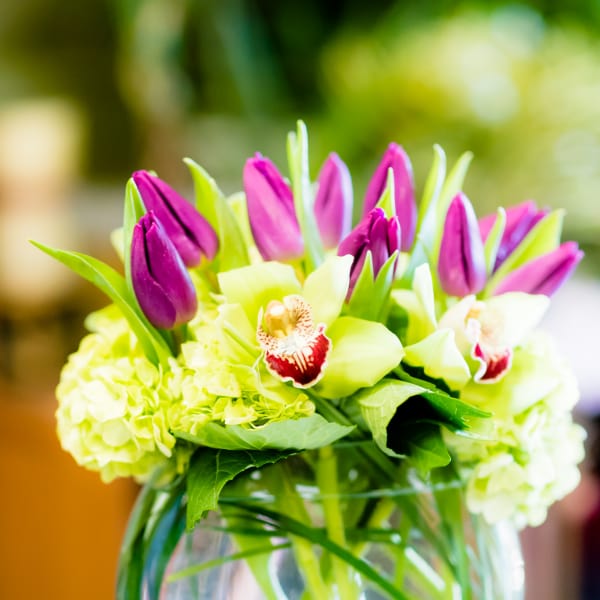 Bouquet of purple tulips and pale green orchids in a glass vase