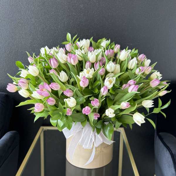 Pink and white tulips in a beige hatbox with a white ribbon