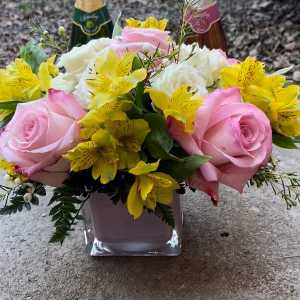 Pink roses and yellow flowers in a square glass vase