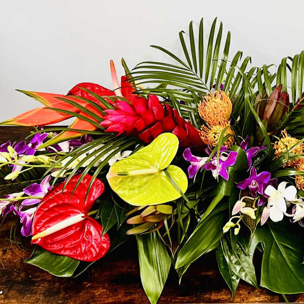 Tropical floral arrangement with red anthuriums, orchids, and palm fronds