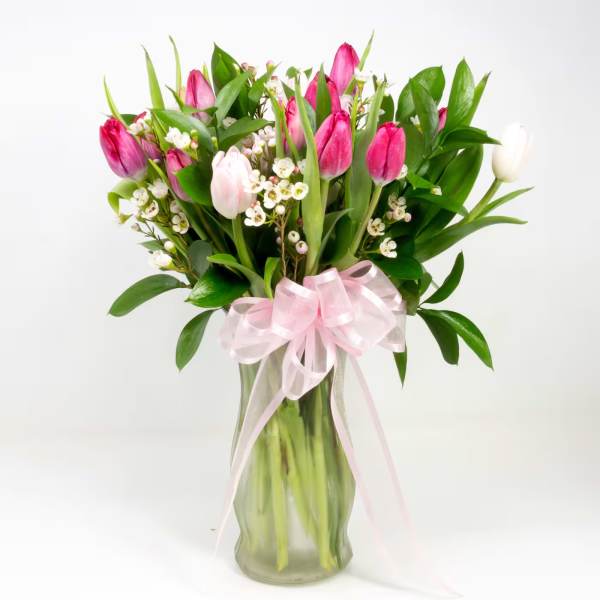 Pink tulips in a glass vase with a pale pink ribbon