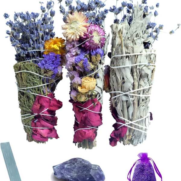 Bundles of dried flowers and herbs with a purple sachet and a blue stone