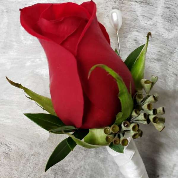 Single red rose boutonniere with green accents and white ribbon wrap