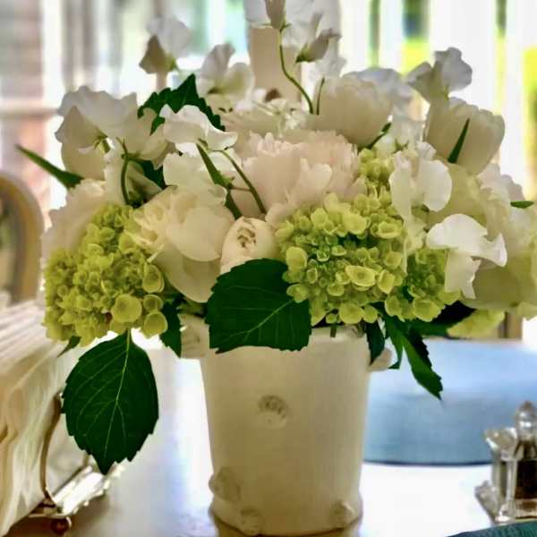 White flowers and pale green hydrangeas in a cream vase