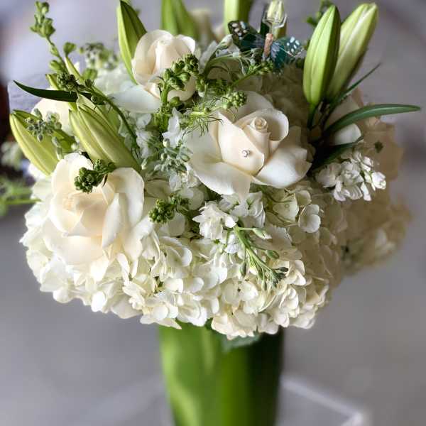 White roses and lilies arranged in a tall glass vase