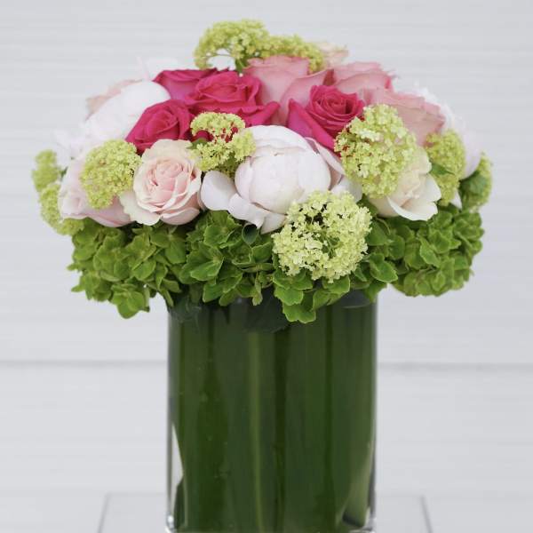 Pink and white roses arranged in a green glass vase