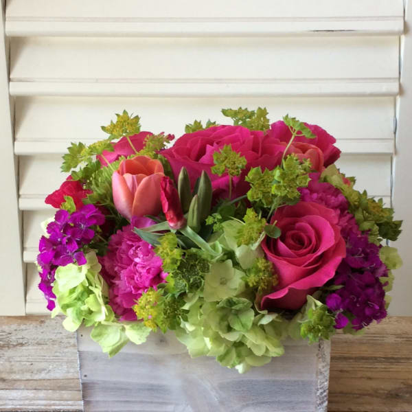 Pink roses and tulips arranged with green hydrangeas in a wooden box
