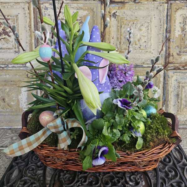 Easter basket with lilies, purple flowers, and decorated eggs