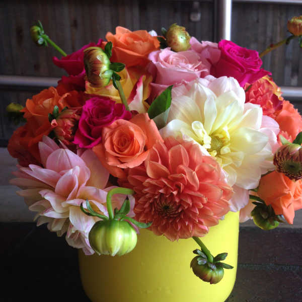 Colorful bouquet of roses and dahlias in a yellow container