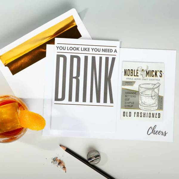 Greeting cards with drink-themed text beside a cocktail glass and pencil sharpener