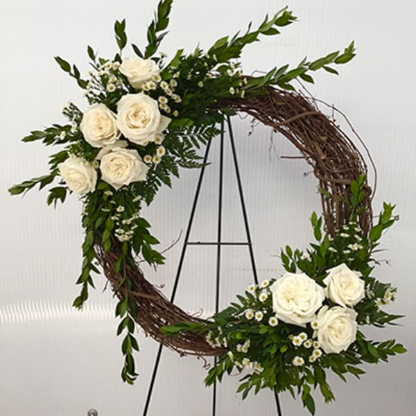 Circular floral wreath with white roses and small white daisies on a twig base