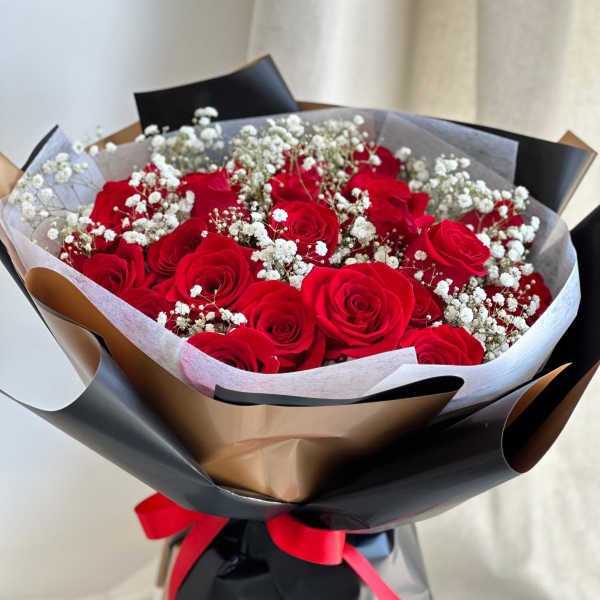 Bouquet of red roses with white baby's breath in black and gold wrapping