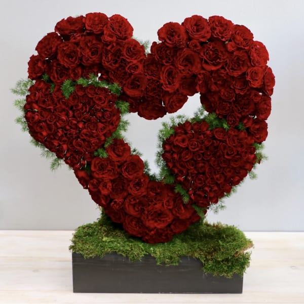 Heart-shaped arrangement of red roses on a moss-covered base