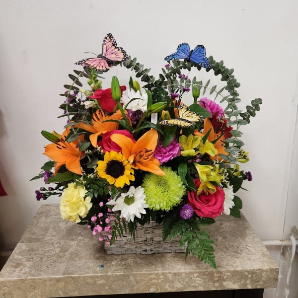 Colorful flower basket with butterfly picks and heart-shaped greenery