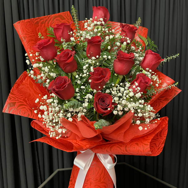 Bouquet of red roses with baby's breath wrapped in bright red paper