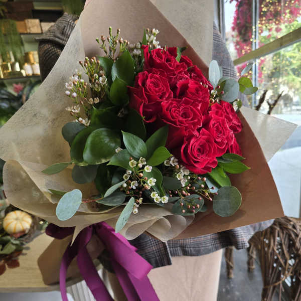 Bouquet of red roses wrapped in brown paper with a purple ribbon