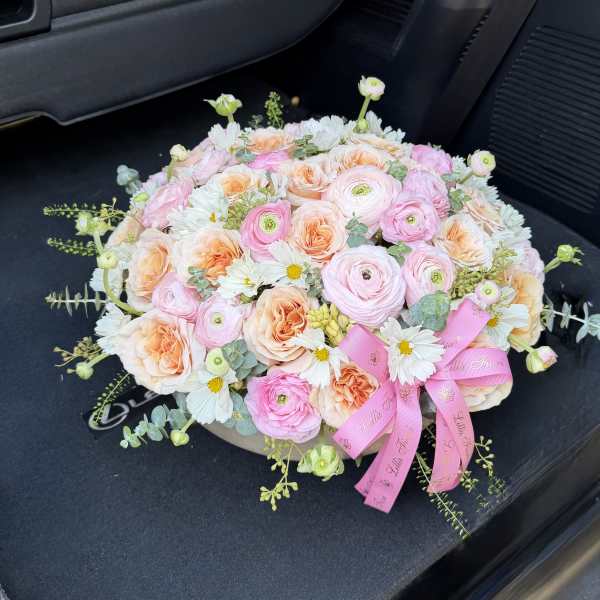 Round bouquet of pink and peach flowers with a pink ribbon