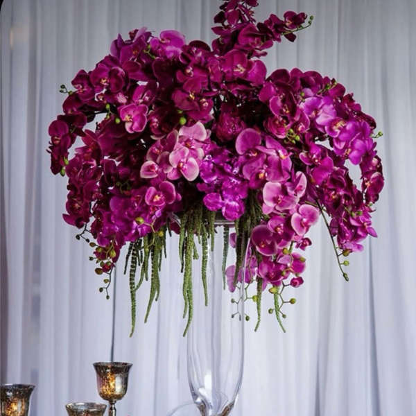 Tall arrangement of purple orchids in a clear glass vase