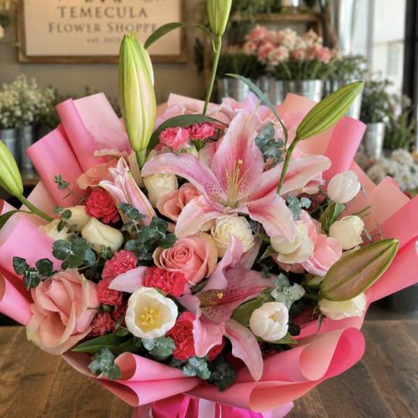 Pink lily and rose bouquet wrapped in bright pink paper