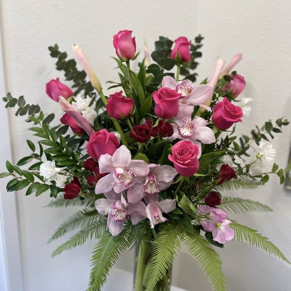 Pink roses and orchids arranged in a clear glass vase