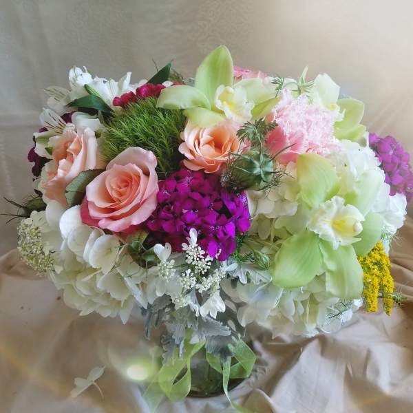Bouquet of pink roses, white hydrangeas, and green orchids in a glass vase